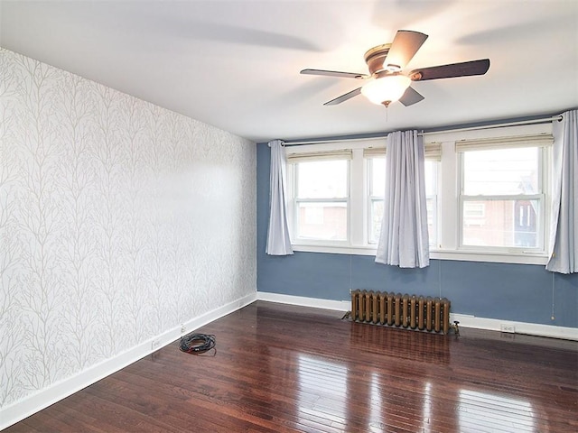 empty room with radiator heating unit, dark wood-type flooring, and a wealth of natural light