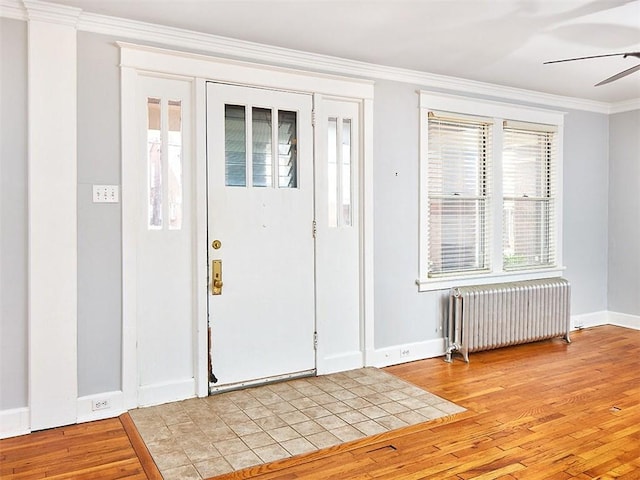 foyer with light hardwood / wood-style floors, radiator heating unit, ornamental molding, and a wealth of natural light