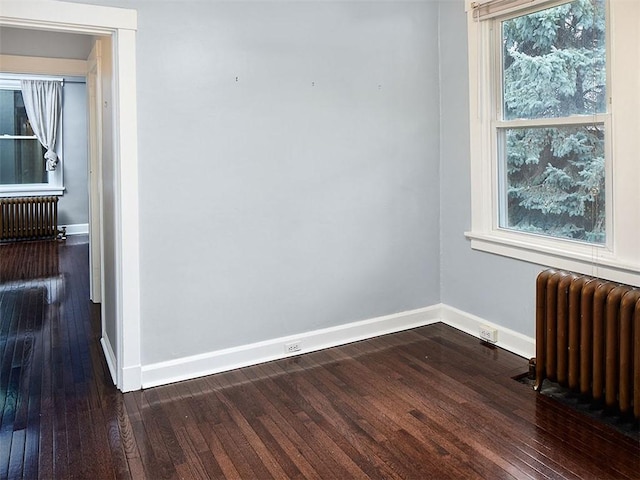 unfurnished room featuring radiator heating unit and dark hardwood / wood-style floors