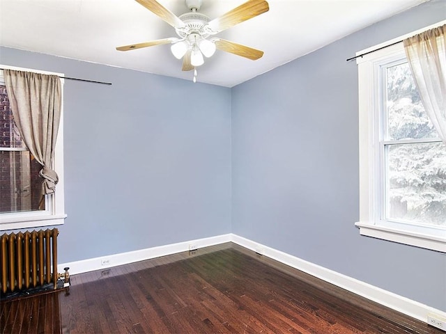 empty room featuring hardwood / wood-style flooring, radiator, and ceiling fan