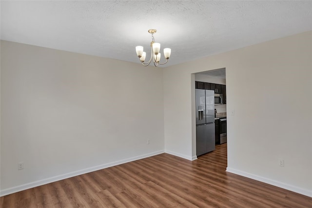 unfurnished room with a chandelier, a textured ceiling, and dark hardwood / wood-style flooring