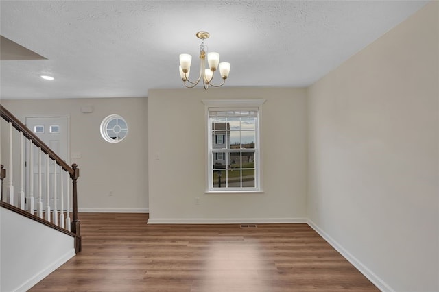 interior space featuring a textured ceiling, dark hardwood / wood-style floors, and an inviting chandelier