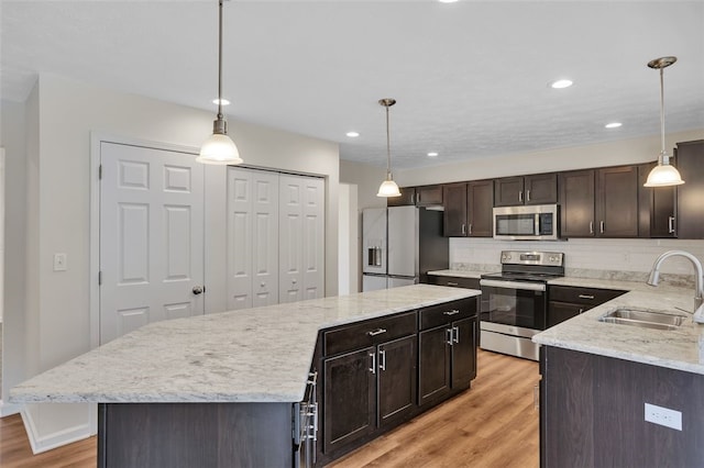 kitchen featuring pendant lighting, a kitchen island, sink, and appliances with stainless steel finishes