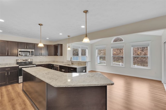 kitchen featuring dark brown cabinets, stainless steel appliances, sink, pendant lighting, and light hardwood / wood-style flooring