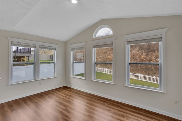 unfurnished room featuring hardwood / wood-style flooring, a textured ceiling, and vaulted ceiling