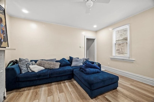 living room with ceiling fan, a fireplace, and light wood-type flooring