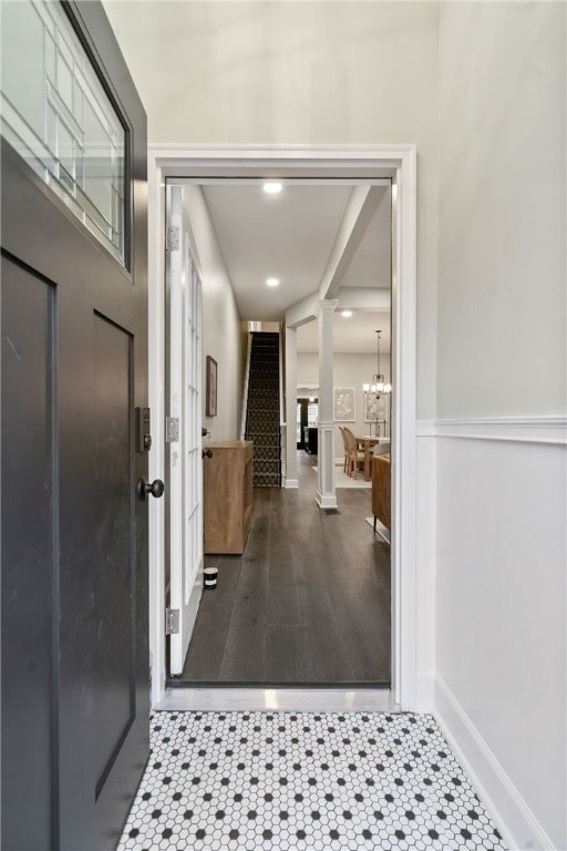 entryway with wood-type flooring, decorative columns, and an inviting chandelier