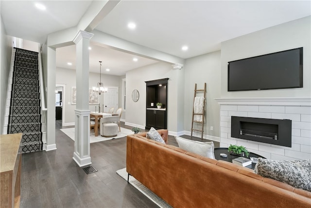 living room with a notable chandelier, beam ceiling, and dark hardwood / wood-style flooring