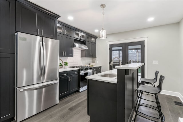 kitchen featuring pendant lighting, sink, an island with sink, appliances with stainless steel finishes, and dark hardwood / wood-style flooring