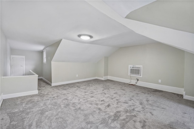 additional living space featuring a wall mounted air conditioner, light colored carpet, and lofted ceiling