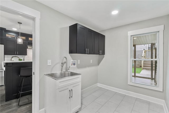 laundry area with cabinets, washer hookup, sink, and light tile patterned flooring