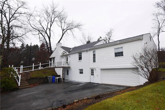 rear view of house featuring a garage and a balcony