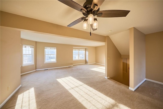 bonus room featuring ceiling fan, light colored carpet, and a healthy amount of sunlight