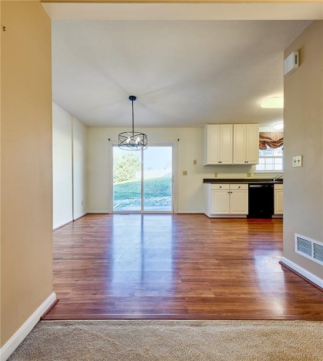 kitchen featuring plenty of natural light, wood-type flooring, black dishwasher, and decorative light fixtures