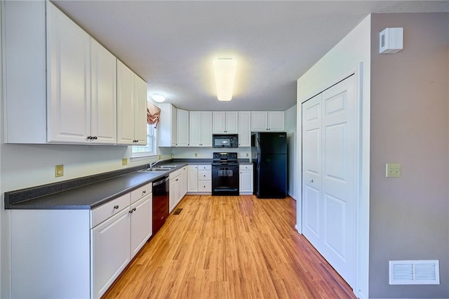 kitchen with sink, light wood-type flooring, white cabinetry, and black appliances