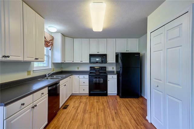 kitchen with black appliances, light wood-type flooring, and white cabinetry