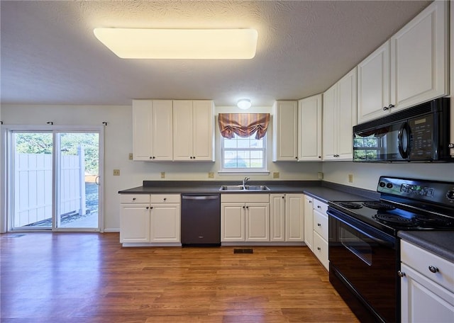 kitchen featuring black appliances, a healthy amount of sunlight, white cabinetry, and sink