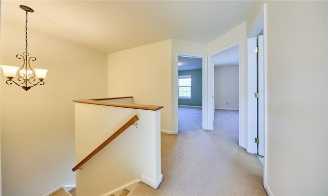 corridor with light colored carpet and a chandelier