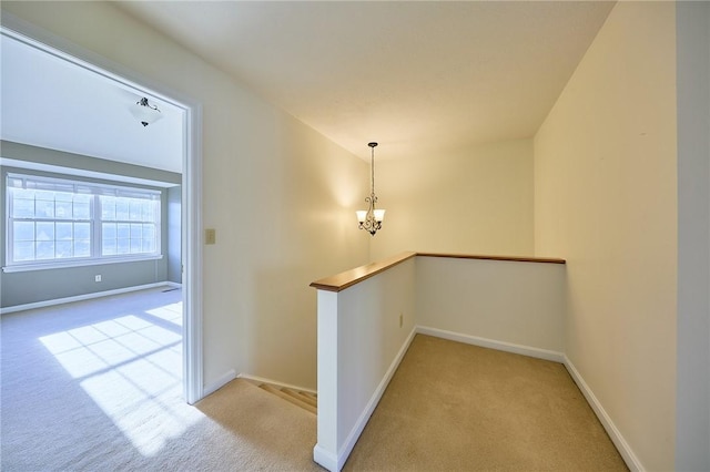 hall featuring light colored carpet and a chandelier