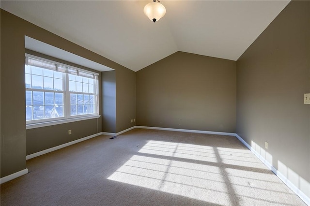 carpeted empty room with lofted ceiling