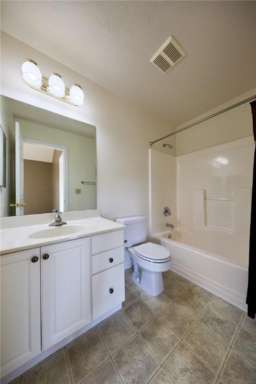 full bathroom featuring vanity, bathing tub / shower combination, tile patterned floors, toilet, and a textured ceiling