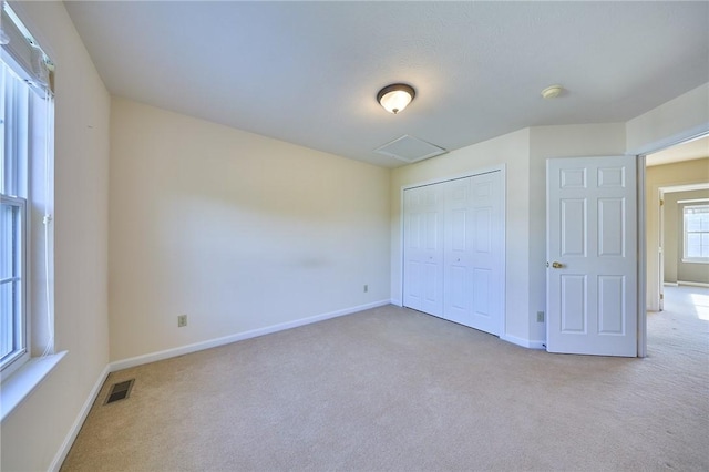 unfurnished bedroom featuring light carpet and a closet