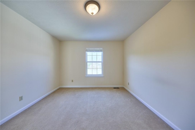 unfurnished room with a textured ceiling and light colored carpet