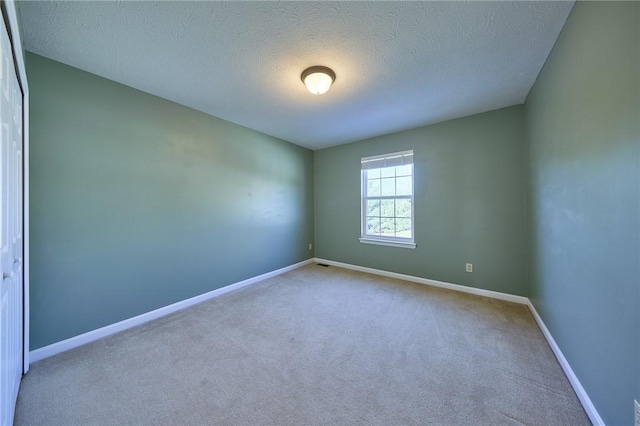 carpeted empty room with a textured ceiling