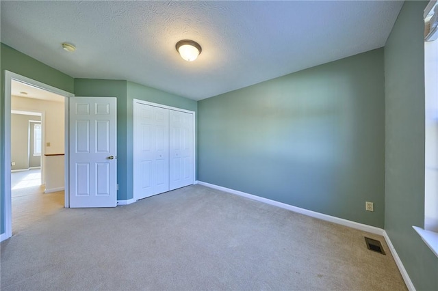 unfurnished bedroom with carpet flooring, a textured ceiling, and a closet