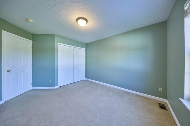 unfurnished bedroom featuring carpet flooring, a textured ceiling, and a closet