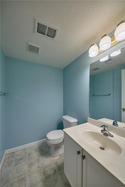 bathroom with tile patterned floors, vanity, toilet, and a textured ceiling