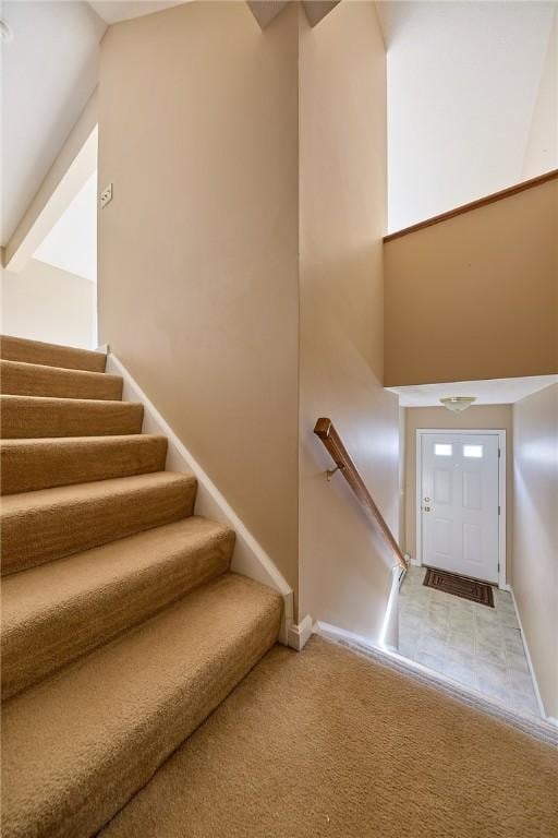 staircase with carpet flooring and high vaulted ceiling