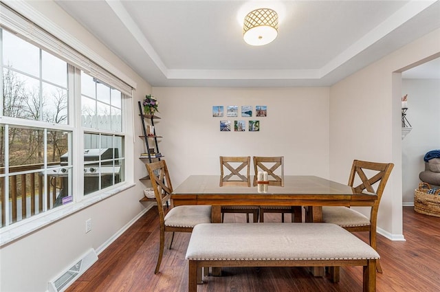 dining room with a raised ceiling and dark hardwood / wood-style floors