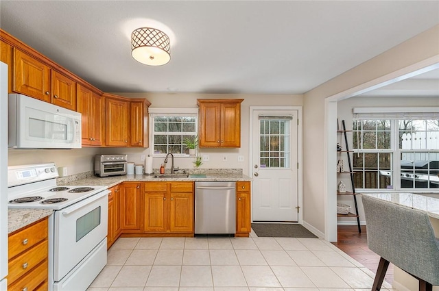 kitchen featuring light stone countertops, sink, light tile patterned floors, and white appliances