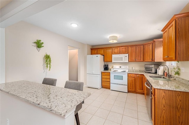 kitchen featuring light stone counters, a breakfast bar, white appliances, and sink