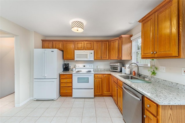 kitchen featuring light tile patterned floors, white appliances, light stone counters, and sink