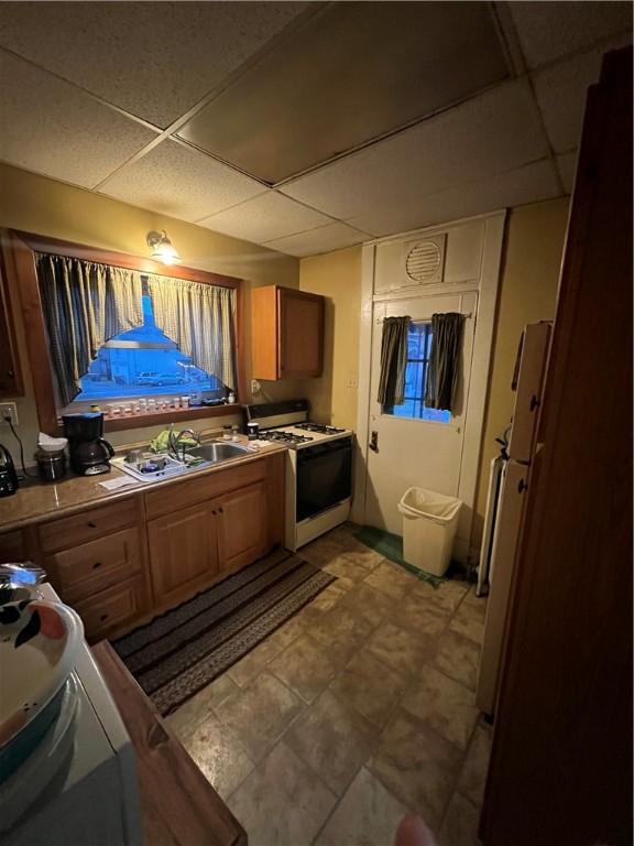 kitchen with sink, a drop ceiling, and white appliances