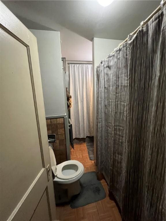 bathroom featuring a shower with curtain, parquet floors, and toilet