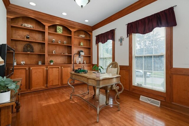 office area with light hardwood / wood-style floors, plenty of natural light, and crown molding