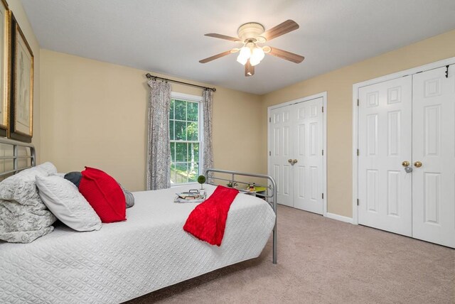 carpeted bedroom with multiple closets and ceiling fan