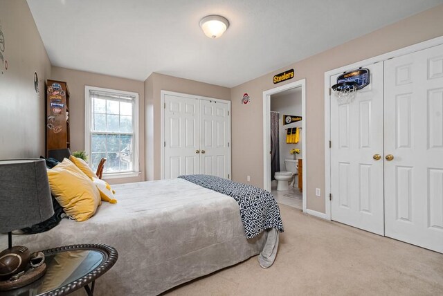 carpeted bedroom featuring connected bathroom and two closets