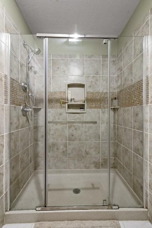 bathroom with a textured ceiling and a shower with shower door