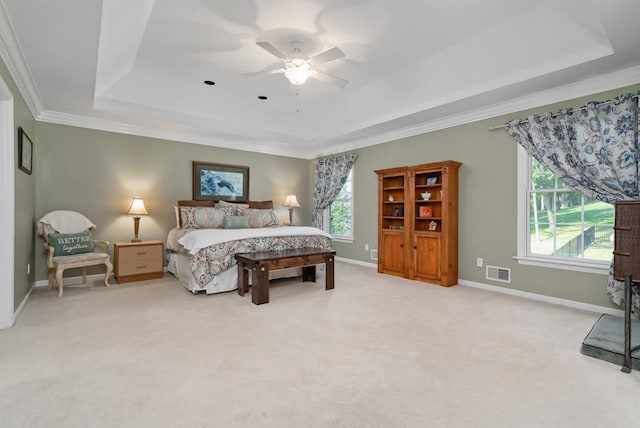 carpeted bedroom with a tray ceiling, ceiling fan, and crown molding