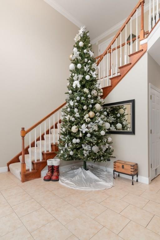 staircase with tile patterned flooring and crown molding