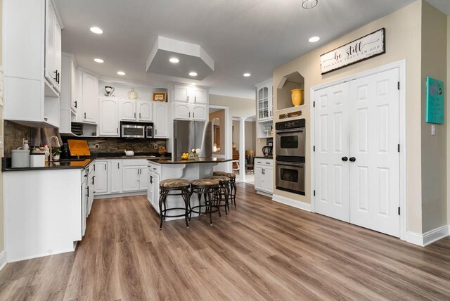 kitchen featuring a kitchen bar, appliances with stainless steel finishes, a kitchen island, hardwood / wood-style floors, and white cabinetry