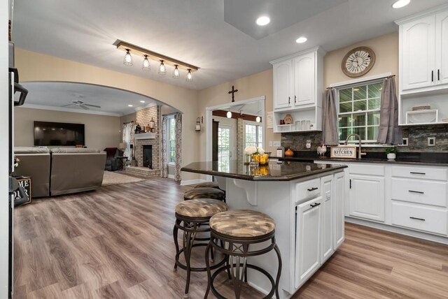 kitchen featuring white cabinets, a kitchen island, ceiling fan, and a breakfast bar area