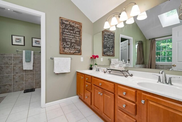 bathroom featuring tile patterned floors, vanity, and vaulted ceiling with skylight