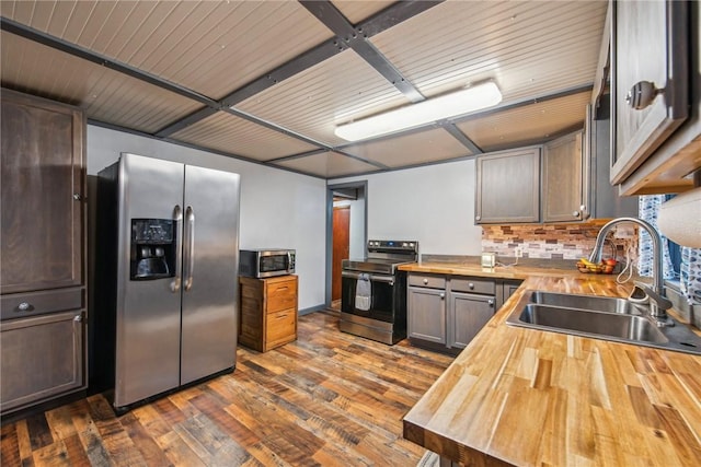 kitchen with backsplash, sink, butcher block countertops, dark hardwood / wood-style flooring, and stainless steel appliances