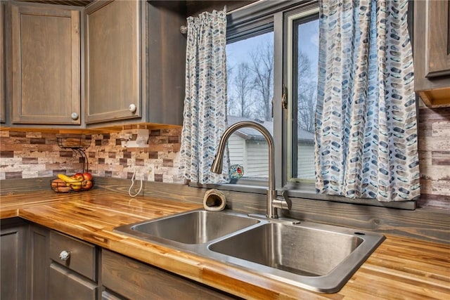 kitchen with butcher block countertops, dark brown cabinetry, decorative backsplash, and sink