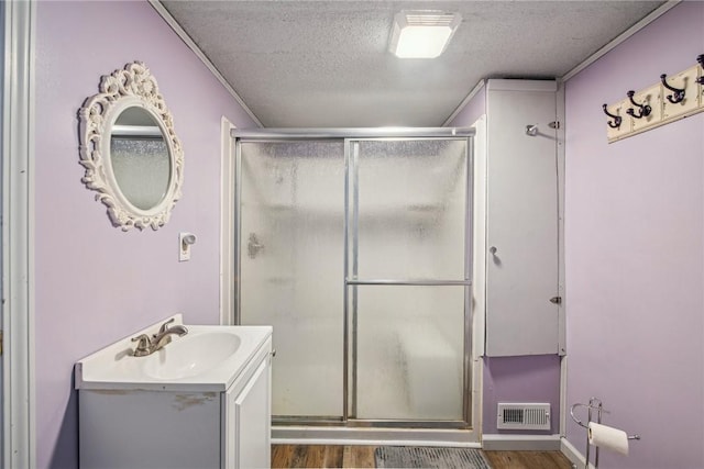 bathroom featuring vanity, wood-type flooring, a textured ceiling, and walk in shower